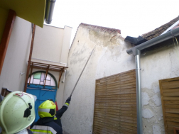 a tűzoltók a leomloó vakolatot távolítják el a debreceni Eötvös utcai házról